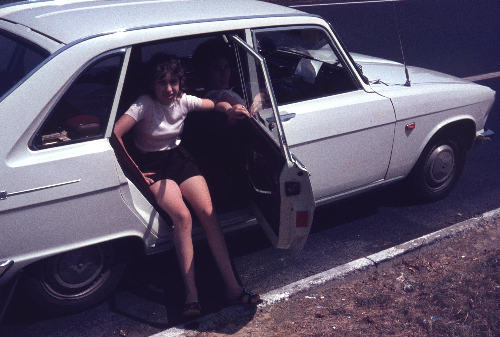 A girl and her mum in a old-timer white car, back door open, a slide from bigkkids'zine